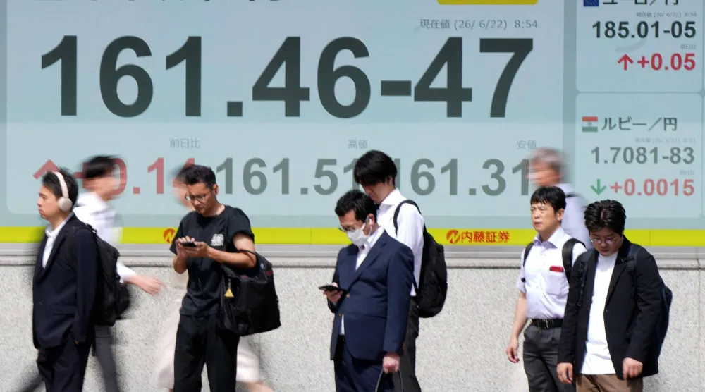 مشاة أمام لوحة إلكترونية تعرض سعر صرف الين الياباني مقابل الدولار الأميركي والعملات الأخرى، على طول أحد شوارع طوكيو (أ.ف.ب)