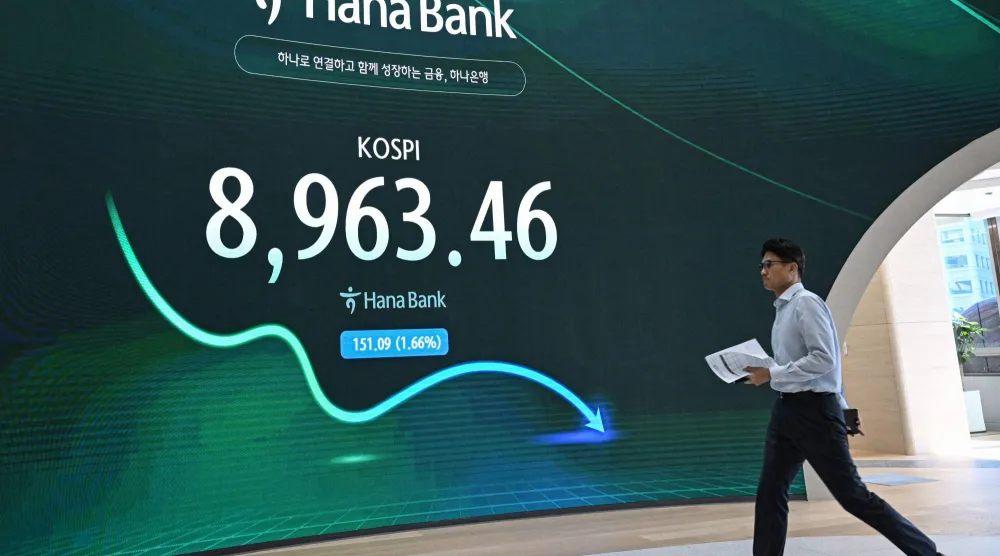 متداول عملات يمر أمام شاشة تعرض مؤشر «كوسبي» في غرفة تداول العملات الأجنبية في بنك هانا بسيول (أ.ف.ب)