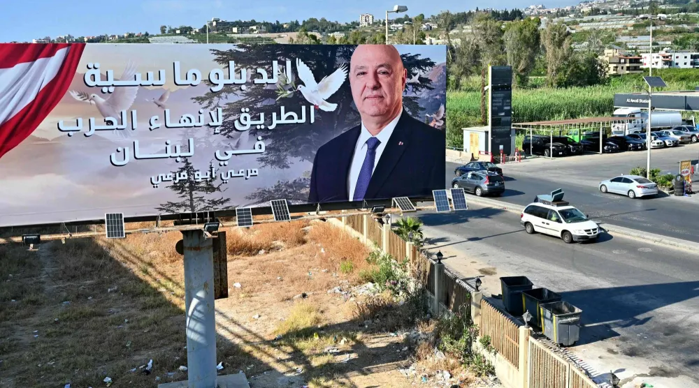 لوحة للرئيس اللبناني جوزيف عون كُتب عليها «الدبلوماسية هي الطريق لإنهاء الحرب في لبنان» على الطريق الساحلي بمدينة صيدا (أ.ف.ب)
