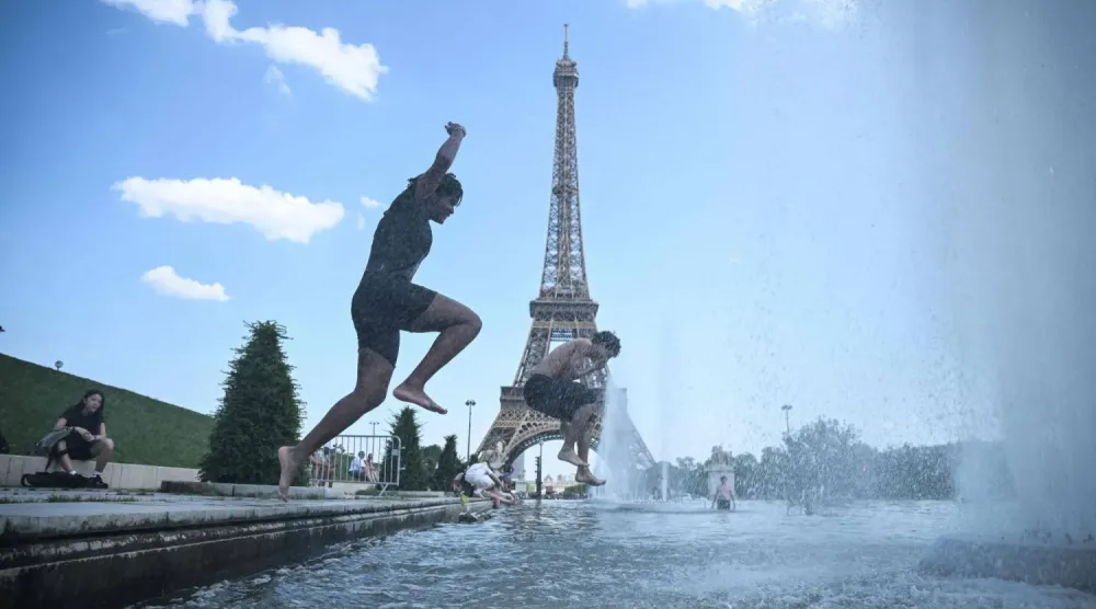 Paris'te etkisini sürdüren sıcak hava dalgası sırasında vatandaşlar, Eyfel Kulesi yakınındaki Trocadéro Çeşmesi'ne girerek serinlemeye çalışıyor. (AFP)