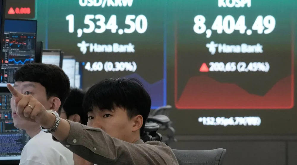 متداول عملات يراقب تحرك أسعار الأسهم قرب شاشة تعرض مؤشر «كوسبي» وسعر صرف العملات الأجنبية بين الدولار والوون الكوري الجنوبي (أ.ب)