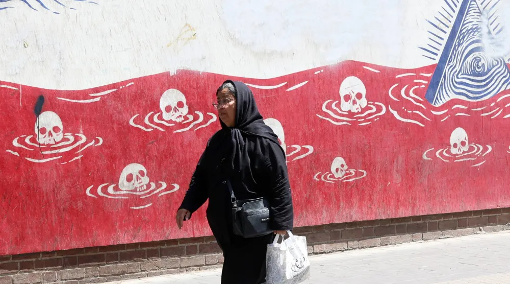 An Iranian woman walks past an anti-US mural next to the former US embassy in Tehran, Iran, 22 June 2026. (EPA)