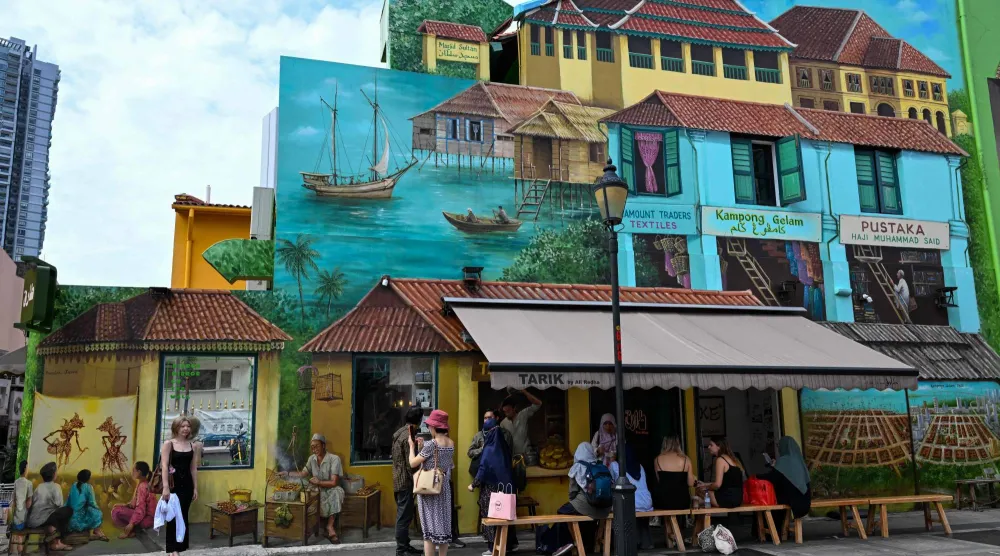 People stop by a cafe with murals painted on its facade in the Arab Street district of Singapore on June 16, 2026. (Photo by Roslan RAHMAN / AFP)