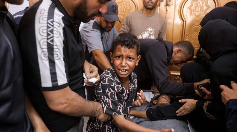 طفل فلسطيني ينتحب بجوار جثمان شقيقه الذي قتلته غارة إسرائيلية في خان يونس جنوب غزة يوم الأربعاء (أ.ف.ب)