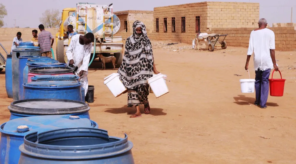 سودانيون يملأون أوعية بالماء في مركز توديع مجاني بالعاصمة الخرطوم (أرشيفية-أ.ب)