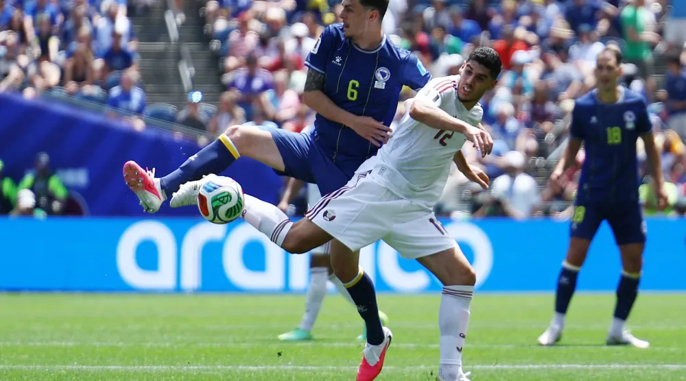 كريم بوضياف لاعب منتخب قطر (يمين) بمواجهة لاعب البوسنة (رويترز)