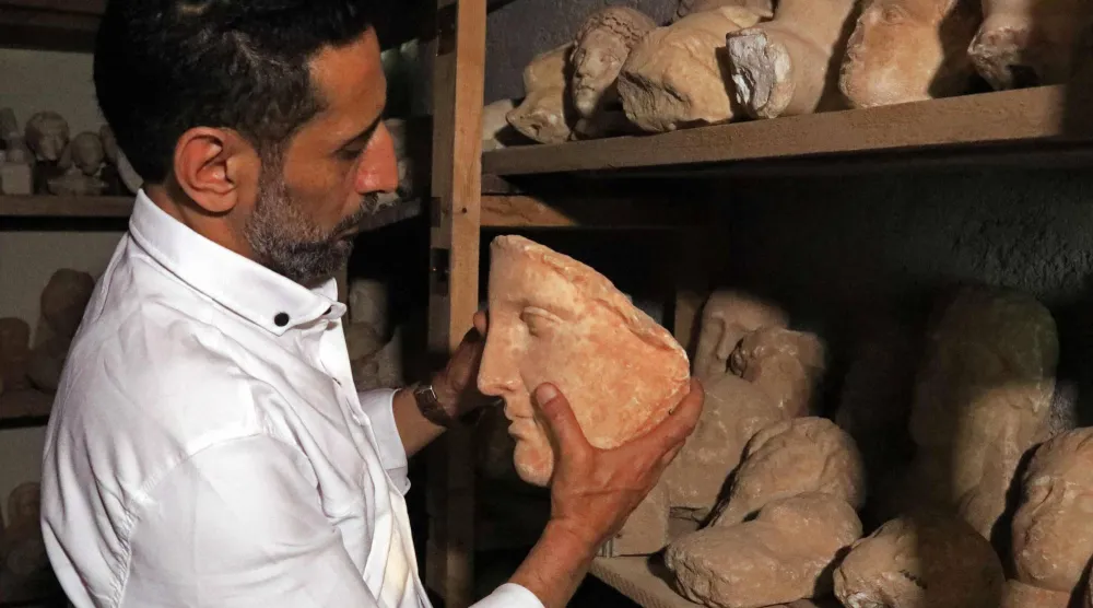 (FILES) A man holds a preserved artifact from the Cyrene archaeological site near the ancient historical town of Shahat in the northeastern Mediterranean coast of Libya on May 17, 2026. (Photo by Abdullah DOMA / AFP)
