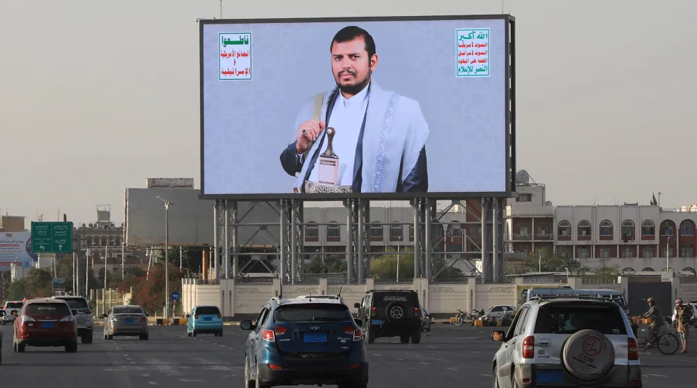 مركبات في العاصمة اليمنية المختطفة صنعاء تمر أسفل لوحة إعلانية تظهر زعيم الحوثيين (أ.ب)