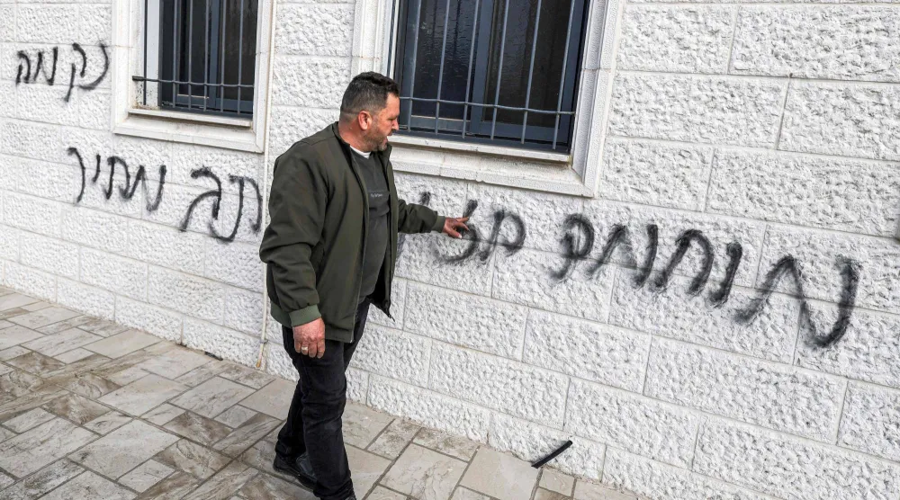 فلسطيني يشير إلى عبارات عنصرية خطَّها مستوطنون على جدران مسجد أبو بكر الصديق في قرية تل غرب نابلس شمال الضفة الغربية (أ.ف.ب)