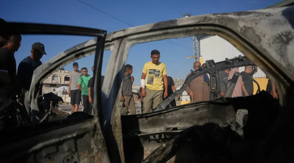  Gazze Şeridi'nin merkezindeki Megazi mülteci kampında İsrail hava saldırısında hedef alınan aracı inceleyen bir Filistinli (AP)