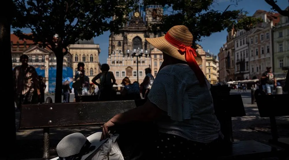 A woman sits in the shade during a hot, sunny day at Old Town Square in Prague, Czech Republic, 27 June 2026. (EPA)