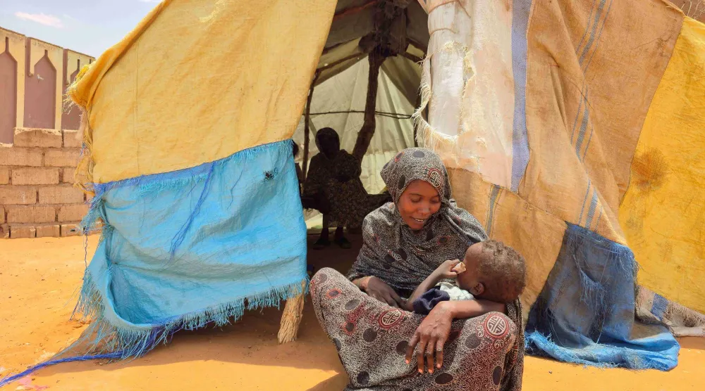 سودانية تجلس مع طفلها في مخيم للنازحين قرب مدينة الأبيض - 25 يونيو 2026 (أ.ف.ب)