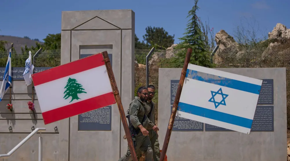 جنديان إسرائيليان عند نصب  على الحدود الشمالية  مرفوع أمامه علما لبنان وإسرائيل (أ.ب)