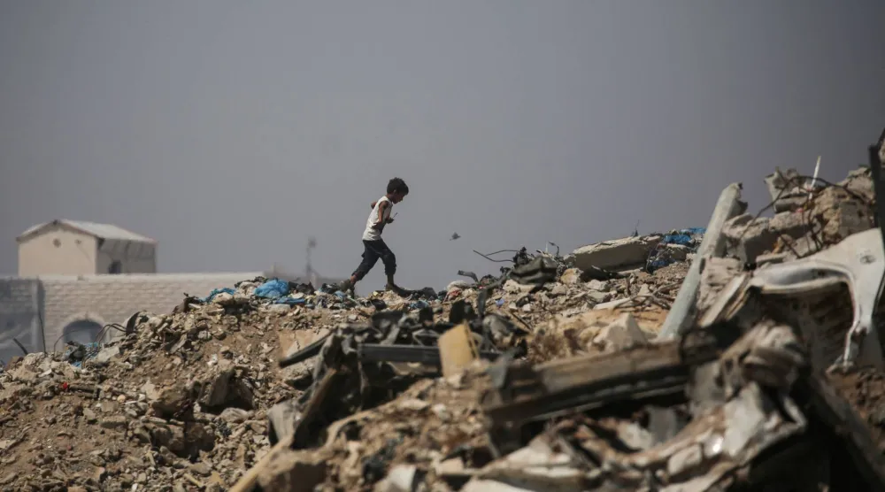 صبي فلسطيني يشق طريقه وسط الأنقاض قرب مخيم للنازحين في منطقة النصيرات وسط غزة يوم الأحد (أ.ف.ب)