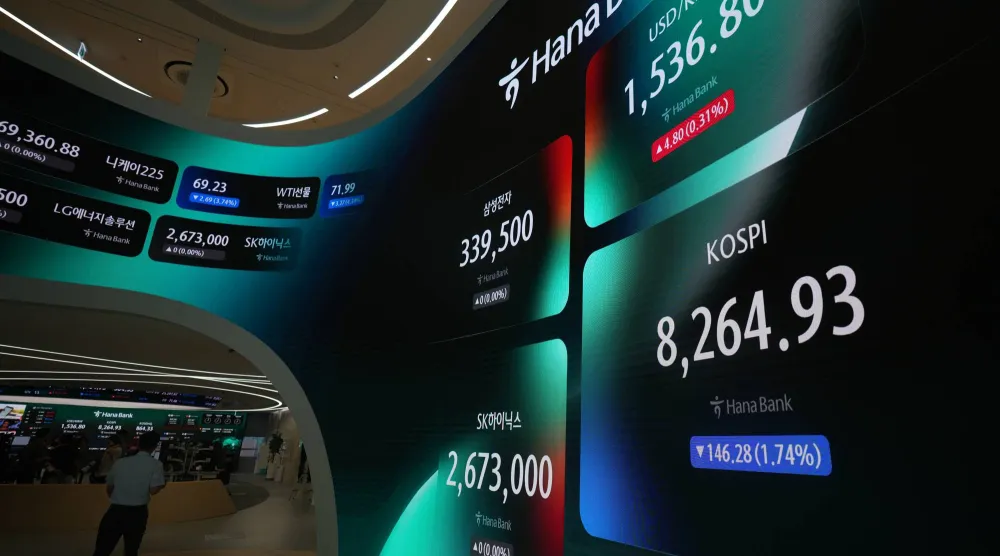 شاشة عملاقة تعرض مؤشر «كوسبي» وسعر صرف العملات الأجنبية بين الدولار والوون الكوري الجنوبي في غرفة تداول ببنك هانا في سيول (أ.ب)