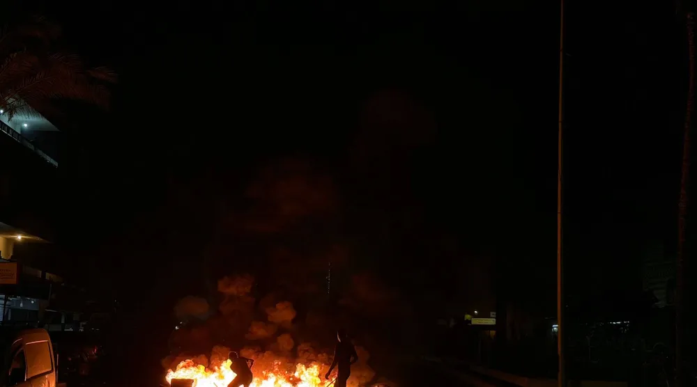 أنصار لـ«حزب الله» يقطعون طريق المطار القديمة في الضاحية الجنوبية لبيروت بإطارات مشتعلة السبت احتجاجاً على الاتفاق الثلاثي الموقع بين الولايات المتحدة وإسرائيل ولبنان 2026 (أ.ف.ب)