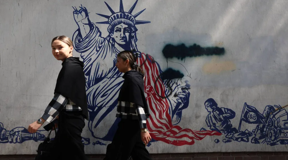 إيرانيتان تمران أمام جدارية مناهضة للولايات المتحدة على حائط سفارتها السابقة في طهران (رويترز)