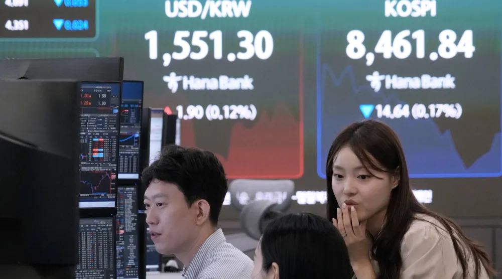 متداولون يعملون قرب شاشة تعرض مؤشر «كوسبي» وسعر صرف العملات الأجنبية بين الدولار والوون الكوري الجنوبي في بنك هانا بسيول (أ.ب)