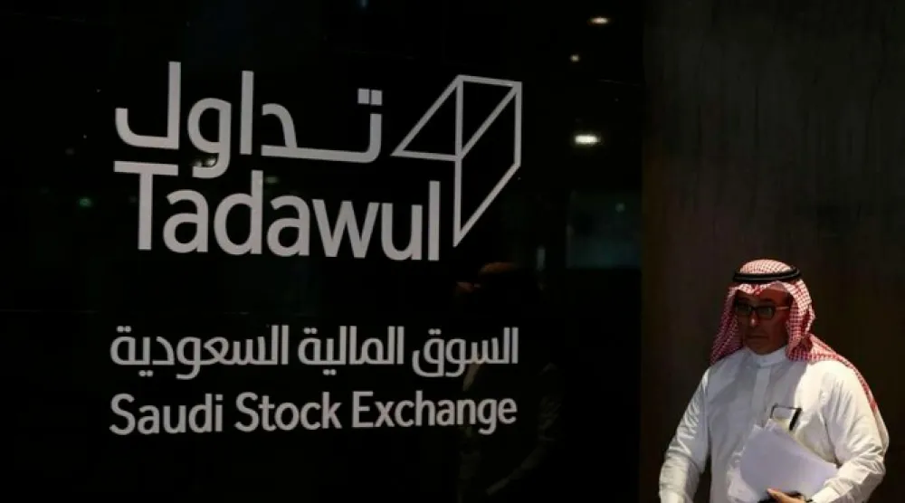 رجل يسير أمام لافتة «تداول» (أ.ف.ب)