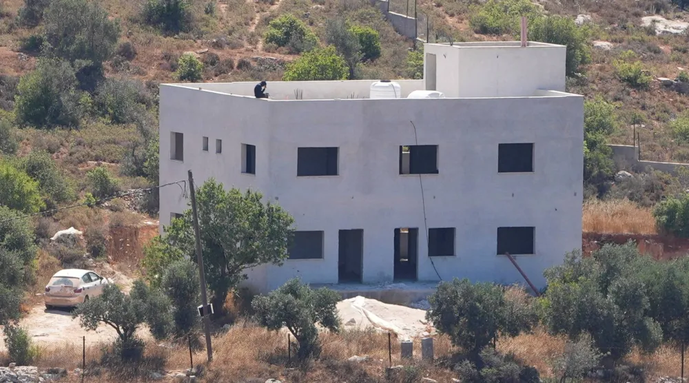 مستوطن إسرائيلي على سطح منزل عائلة سلامة الفلسطينية الذي استولى عليه مستوطنون إسرائيليون في قرية جالود بالضفة الغربية التي تحتلها إسرائيل في 2 يوليو 2026 (رويترز)