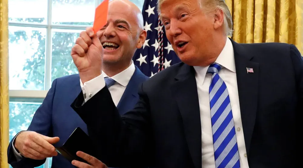 ABD Başkanı Trump, FIFA Başkanı Infantino’nun yanında şaka yollu olarak fotoğrafçıların objektifleri karşısında kırmızı kart gösterirken (Reuters)