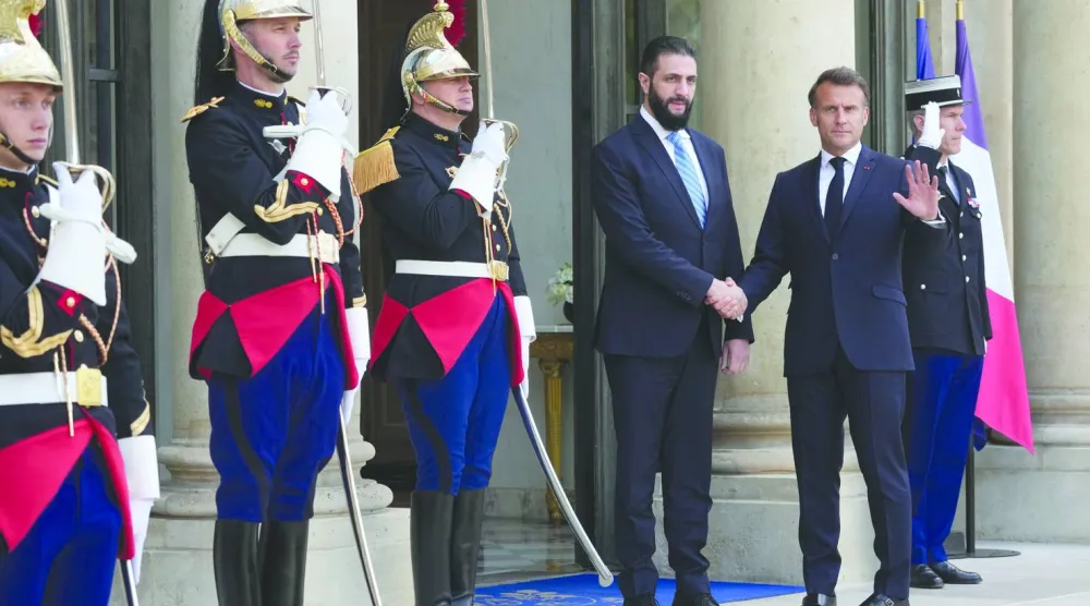 الرئيس الفرنسي إيمانويل ماكرون مستقبلاً الرئيس السوري أحمد الشرع على مدخل قصر الإليزيه في باريس مايو الماضي (أ.ب)