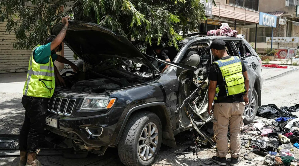 مسعفون وعناصر إنقاذ يعاينون السيارة التي استهدفت بغارة إسرائيلية في النبطية بجنوب لبنان وأدت إلى مقتل 4 أشخاص (أ.ف.ب)