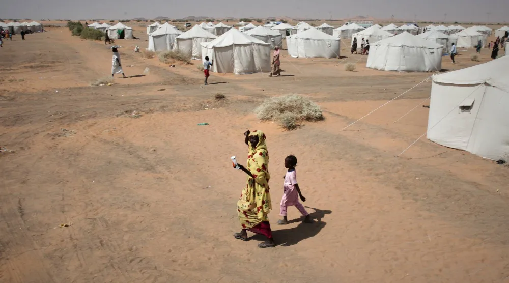 امرأة وطفل سودانيان نازحان يسيران في مخيم العفاض الذي أُنشئ حديثاً بالضبعة - الولاية الشمالية 13 نوفمبر 2025 (أ.ب)