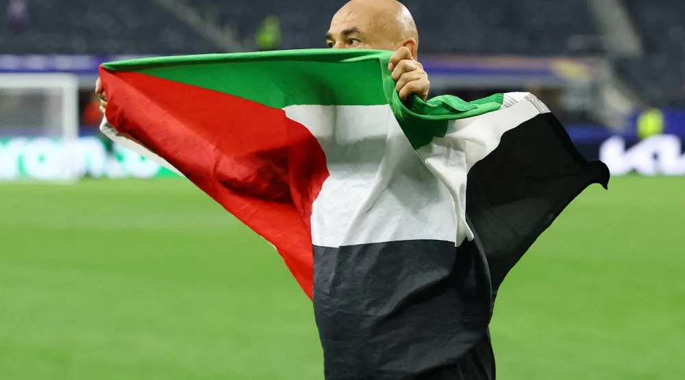 حسام حسن يرفع العلم الفلسطيني بعد فوز مصر على أستراليا والتأهل للدور 16 في كأس العالم لكرة القدم (رويترز)