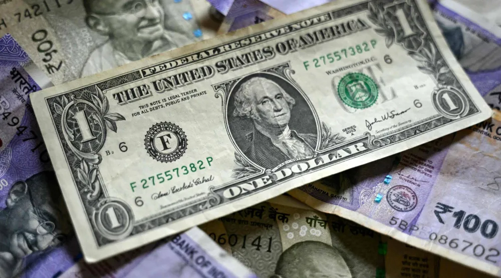 ورقة نقدية من فئة الدولار موضوعة فوق أوراق نقدية من فئة الروبية الهندية في بنغالورو (أ.ف.ب)