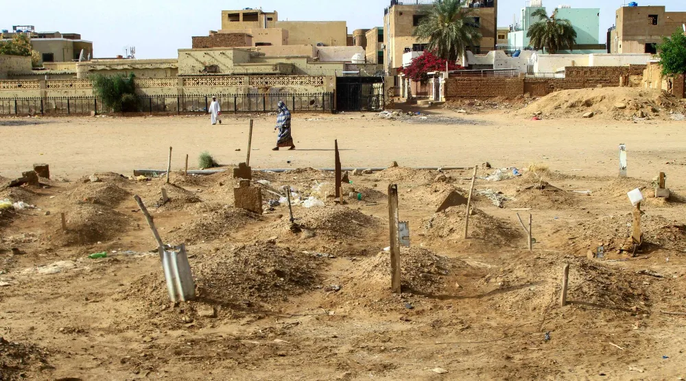امرأة سودانية تسير بين مدافن سودانيين في أم درمان قتلوا في الحرب (أ.ف.ب) 