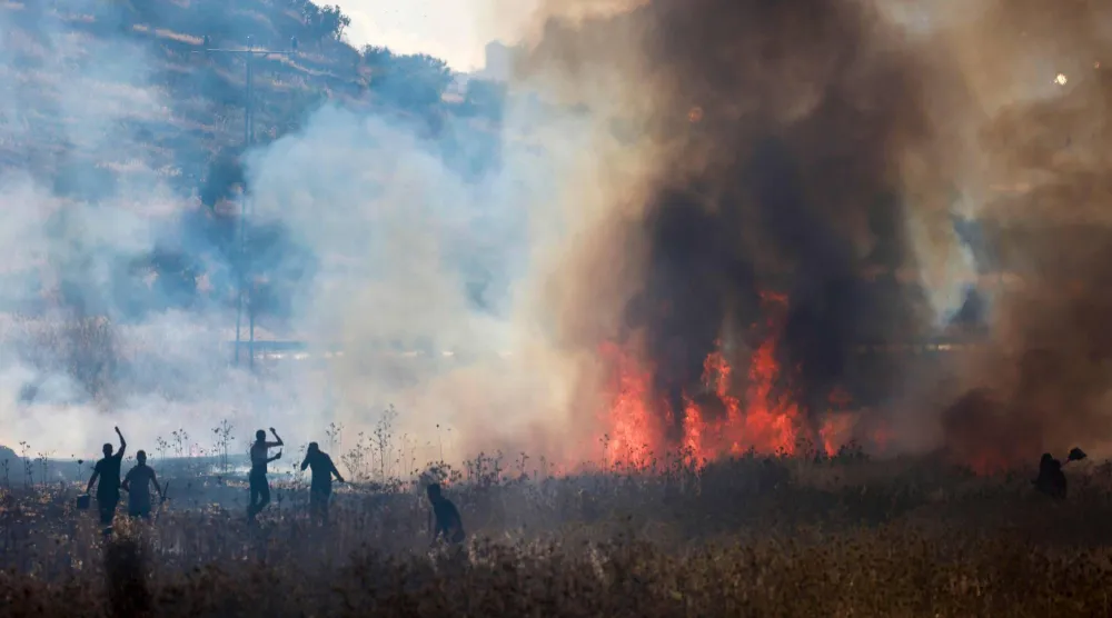 فلسطينيون يحاولون إخماد حريق أشعله مستوطنون في حقول قمح بقرية سالم شرق نابلس في الضفة الغربية المحتلة يوم الجمعة (أ.ف.ب)