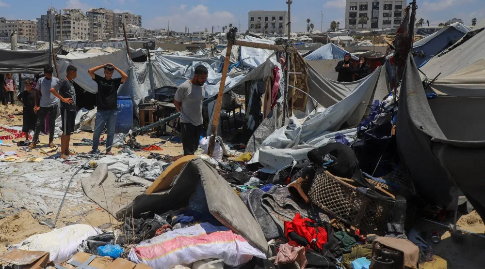 فلسطينيون يتفقدون موقع غارة إسرائيلية استهدفت خيمة في مخيم لإيواء النازحين بمدينة غزة (رويترز)