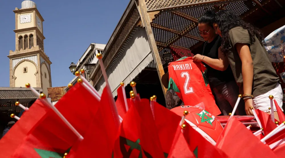أشخاص يشترون قمصان المنتخب المغربي من بائع متجول في الدار البيضاء قبل مواجهة المغرب وفرنسا (رويترز)