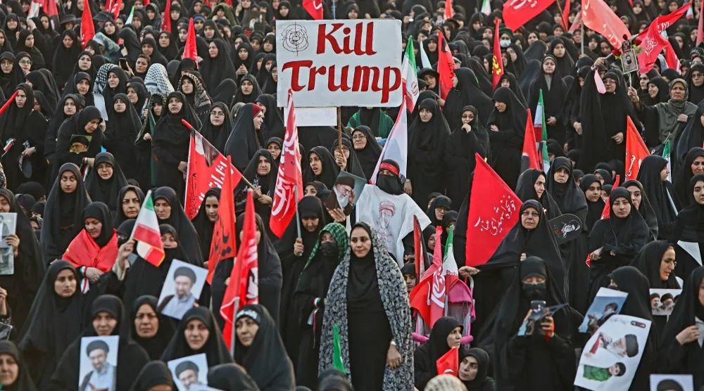جانب من موكب جنازة المرشد الإيراني الراحل علي خامنئي في مدينة قم... وتظهر لافتة بين الحضور تدعو لقتل الرئيس الأميركي دونالد ترمب (رويترز)