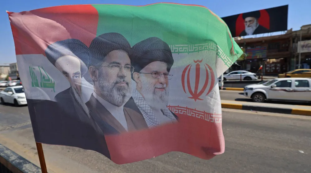 علم يحمل صور المرشد الإيراني الراحل علي خامنئي وابنه المرشد الحالي مجتبى خامنئي منصوباً على جانب أحد الشوارع في مدينة كربلاء بالعراق يوم 7 يوليو 2026 (أ.ف.ب)