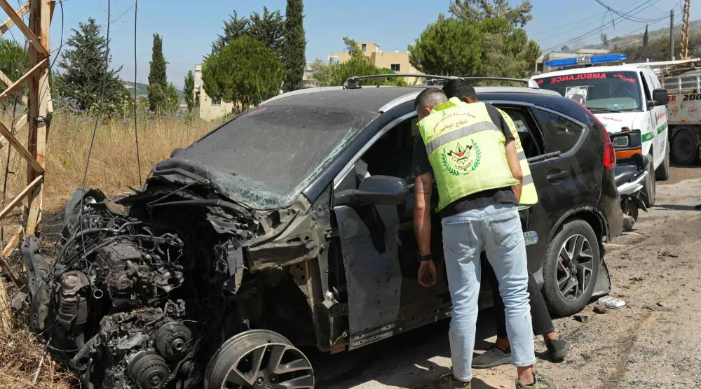 أحد عناصر الدفاع المدني اللبناني يتفقد سيارة استهدفتها غارة إسرائيلية في كفر رمان بجنوب لبنان (أ.ف.ب)