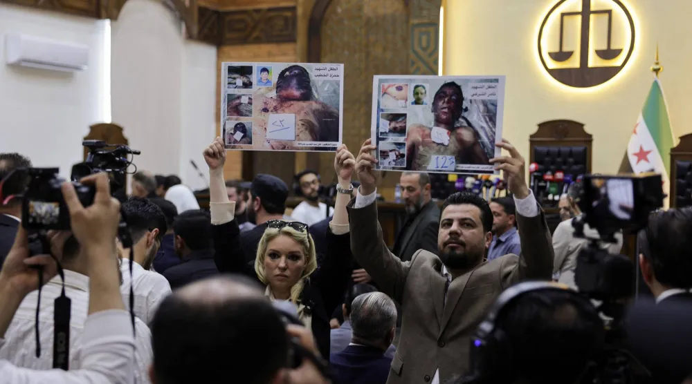 متظاهرون يحملون صور ضحايا تعذيب خلال جلسة محاكمة عاطف نجيب في «قصر العدل» بدمشق يوم 26 أبريل 2026 (رويترز)