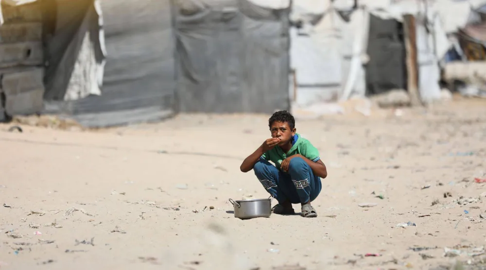 طفل فلسطيني نازح يتناول الطعام في منطقة الزرقاء بمدينة غزة وسط أزمة النزوح المستمرة ونقص الإمدادات الإنسانية الناجم عن الحرب (د.ب.أ)