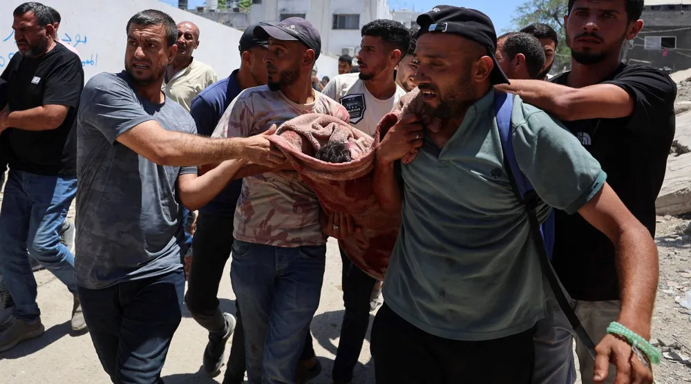 فلسطينيون خارج مستشفى الشفاء في مدينة غزة يحملون جثمان أحد الضباط الفلسطينيين الذين قتلوا في غارة إسرائيلية على مركز للشرطة(رويترز)