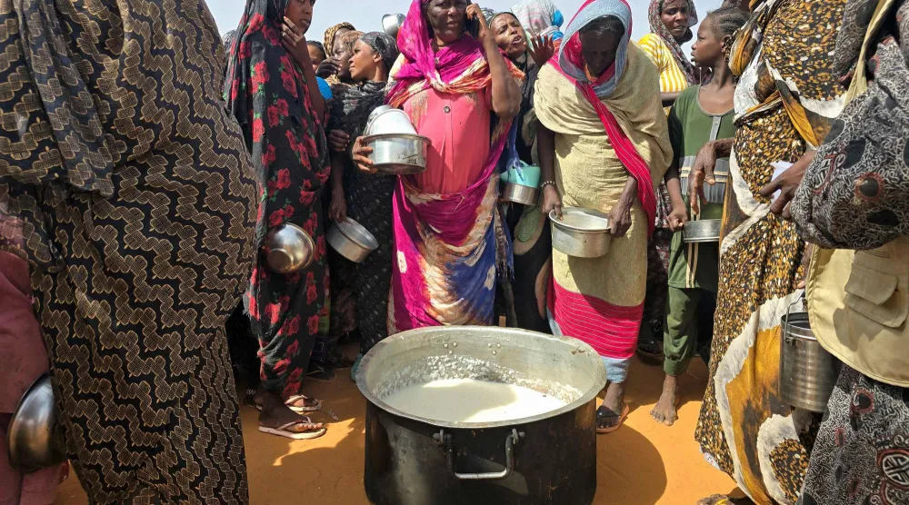 تتجمع نساء سودانيات لتناول وجبة ساخنة في مخيم الرحمانية للنازحين بالقرب من مدينة الأبيض في منطقة كردفان الجنوبية (أ.ف.ب)