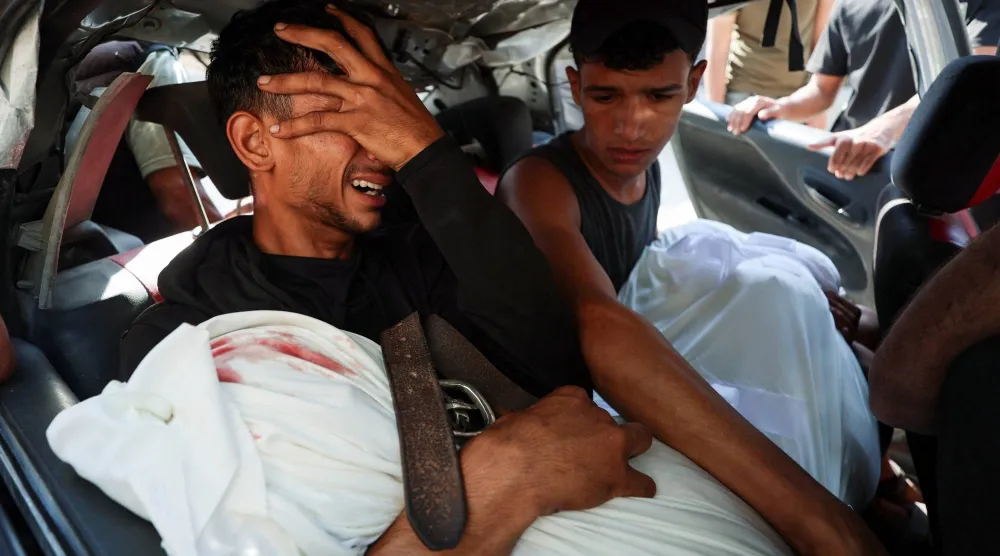 فلسطيني يحتضن جثمان والده الذي قُتل في غارة إسرائيلية بمدينة غزة يوم الخميس (رويترز)