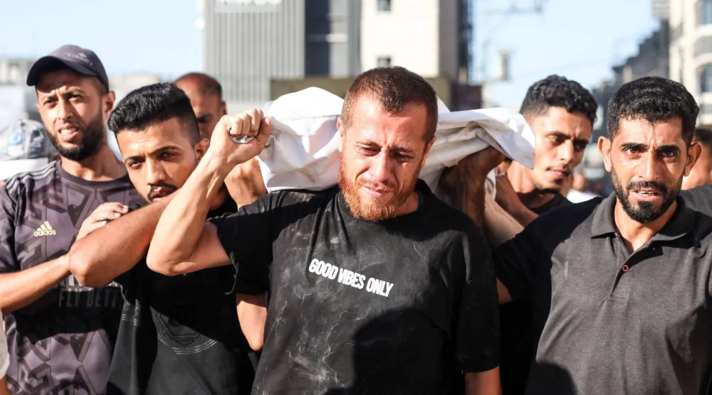فلسطينيون يحملون جثماناً آخر قتل في غارة إسرائيلية على مخيم النصيرات (د.ب.أ)