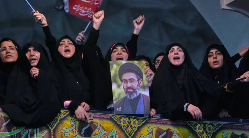 Mourners chant slogans as one of them holds a poster of the Supreme Leader, Mojtaba Khamenei, in a ceremony commemorating the late Supreme Leader, Ali Khamenei, in Tehran, Tuesday, July 14, 2026. (AP Photo/Vahid Salemi)