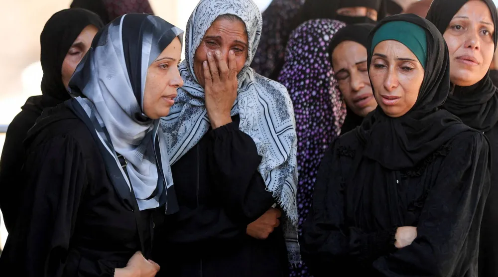 فلسطينيات يبكين يوم الأحد خلال جنازة ضحايا غارة إسرائيلية على مدينة غزة (رويترز)