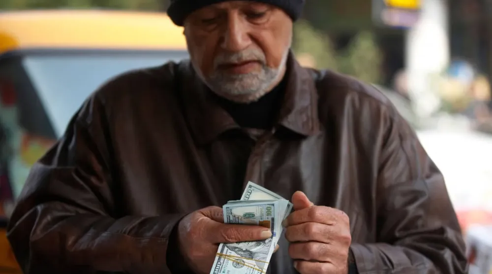 27 Aralık 2022 tarihinde Bağdat’taki el-Kifah pazarında bir adam ABD doları banknotlarını sayıyor. (AFP)