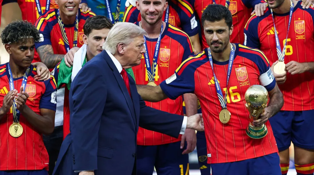 لم يغادر ترمب المنصة كما جرت العادة بل بقي واقفاً إلى جانب لاعبي إسبانيا أثناء لحظة رفع الكأس (أ.ف.ب) 
