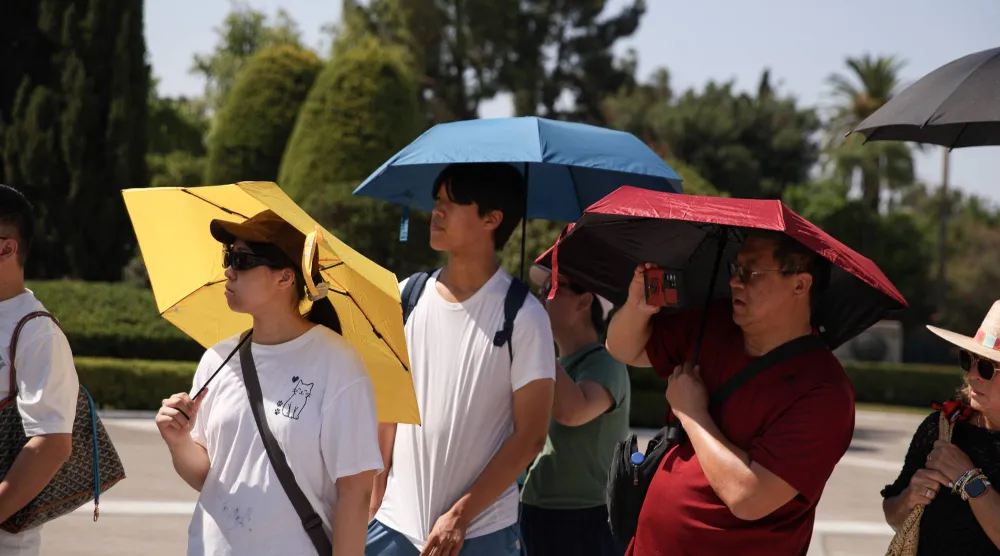  20 July 2026, Greece, Athens: Tourists use umbrellas to shield themselves from the sun during a hot weather. Greece is experiencing its first major heatwave of the summer. (dpa)