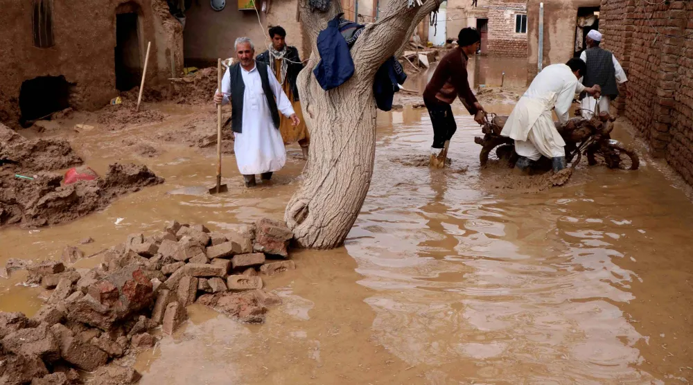 سكان ينتشلون أغراضاً من منزل دمّره الفيضان في منطقة إنجيل بولاية هرات بأفغانستان (أرشيفية - رويترز)