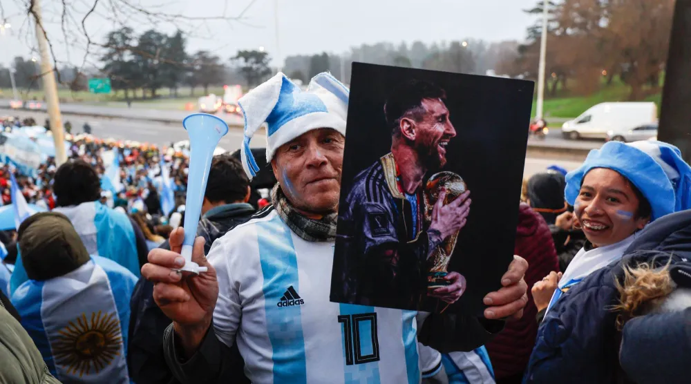 رجل يرفع صورة ليونيل ميسي في نهائي كأس العالم 2022 بينما يرحب المشجعون بالمنتخب الوطني بعد عودته من كأس العالم 2026 (إ.ب.أ)